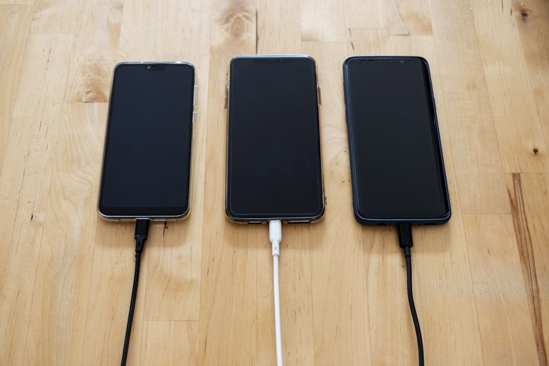 Smartphone placed on a circular wireless charging pad on a wooden desk